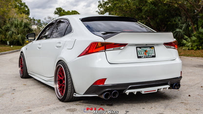 A white Lexus sedan shown from the rear three-quarter angle, featuring a custom black rear diffuser, dual exhaust, and red multi-spoke wheels. The car is parked outdoors on a paved surface with trees in the background.