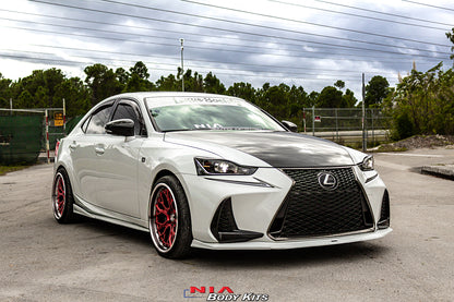 A white Lexus sedan parked outdoors on a paved lot, featuring a black carbon fiber hood, black front grille, and red multi-spoke wheels. A 'NIA Body Kits' logo is visible at the bottom of the image.